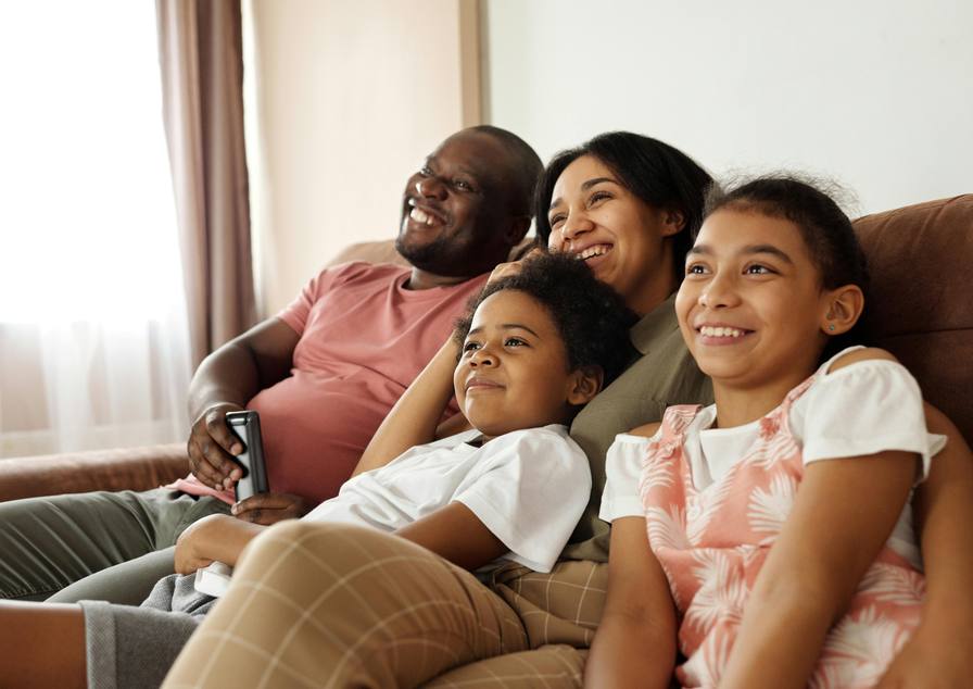 Gezin met twee kinderen kijkt samen tv op de bank